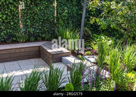 Cozy shady seating area made of concrete and wood in a garden Stock Photo