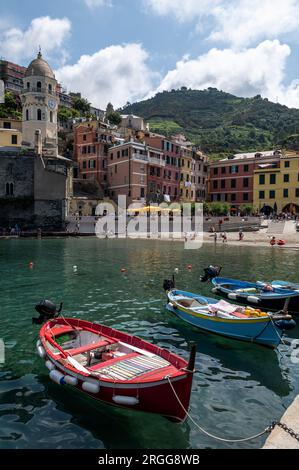 A small harbour front with moored fishing boats near a small Piazza (Square) filled with a mix of eateries, ice cream parlours and the prominent Santa Stock Photo