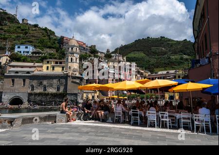 A small harbour and a small Piazza (Square) filled with a mix of eateries, ice cream parlours and the prominent Santa Margherita di Antiochia Church a Stock Photo