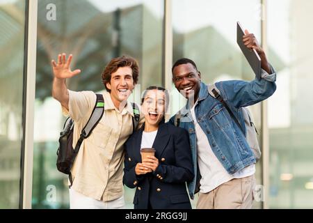 Happy multiracial students waving at camera and smiling Stock Photo