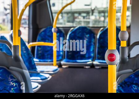 Stop button on the modern public transport bus. Empty bus interior. Public transport in the city. Passenger transportation. Bus with blue seats and ye Stock Photo