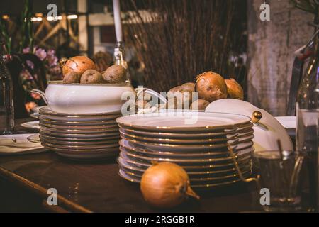 Stacked plates with gold rim and bowl with onions on an old wooden table Stock Photo
