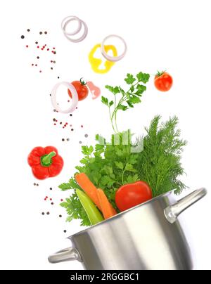 Fresh vegetables falling into a cooking pot isolated on white transparent background Stock Photo