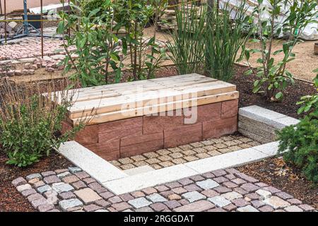 Cozy shady seating area made of concrete and wood in a garden Stock Photo
