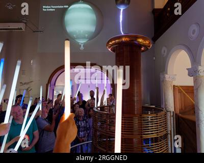 People enjoying an experiment with wands in their hands as a bolt of lightning appears in the Nikola Tesla Museum, Belgrade, Serbia. August 9, 2023. Stock Photo