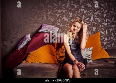 Young woman sitting on sofa at nightclub Stock Photo