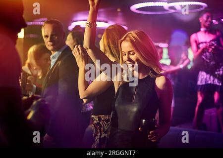 Young woman dancing with friends at nightclub Stock Photo