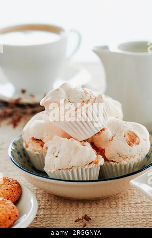 closeup of some merengues almendrados, spanish baked meringues with almonds, in a ceramic bowl on a table set with a brown tablecloth Stock Photo