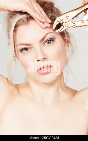 Young woman using pliers on her eyebrow Stock Photo