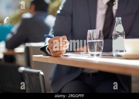 Hand of businessman making notes at cafe Stock Photo