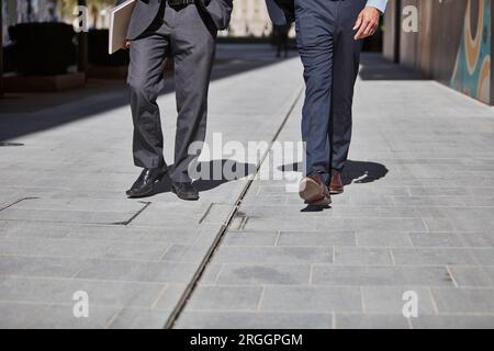 Legs of businessmen walking on sidewalk Stock Photo