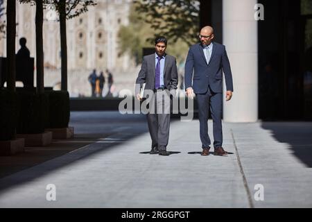 Businessmen walking along sidewalk together Stock Photo