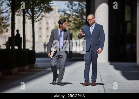 Businessmen walking along sidewalk together Stock Photo