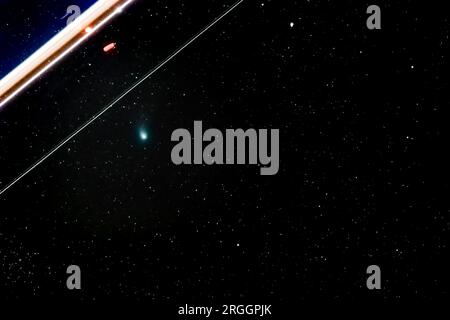 Long time exposure of Green Comet C/2022 E3 (ZTF) in the night sky with tracer of an airplane at 428mm on February 12, 2023 near Darmstadt, Germany Stock Photo
