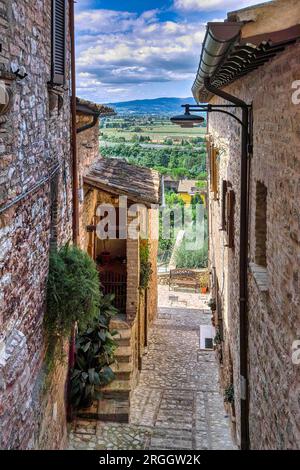 Town of Spello, Umbria, Italy. Characteristic narrow cobbled street, flanked by houses of medieval origin and with a view of the countryside below. Stock Photo