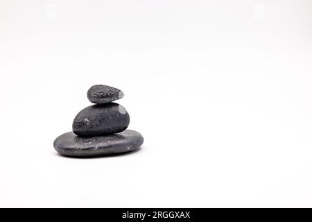 A cairn made of three black stones on white background cropped in studio Stock Photo