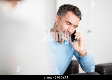 Mature businessman talking on smartphone in office Stock Photo