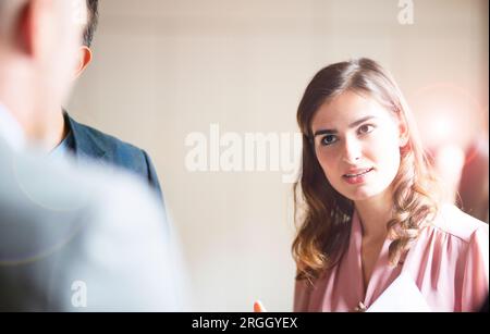 Young businesswoman talking to colleagues in office Stock Photo