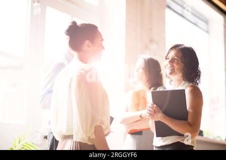 Mature businesswomen talking by window in office Stock Photo