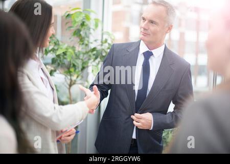 Businesspeople shaking hands by window Stock Photo
