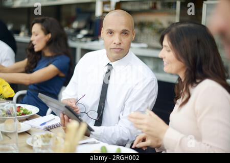 Businesspeople using tablet PC at restaurant meeting Stock Photo