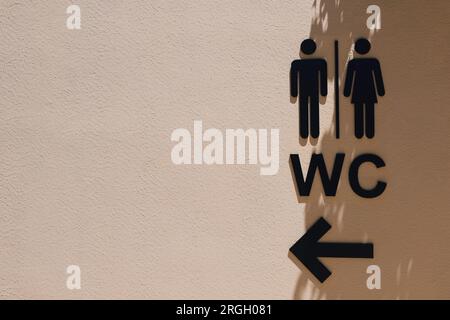 Black male and female public restroom sign with right direction on the wall with shadows.Toilets man and woman icon. WC sign icon. Stock Photo
