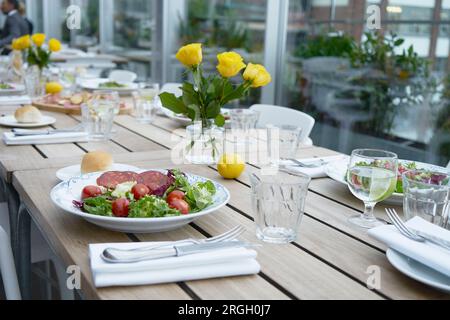Salad on set table with yellow roses Stock Photo