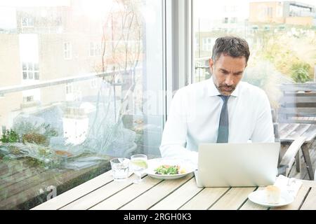Businessman using laptop by window in restaurant Stock Photo