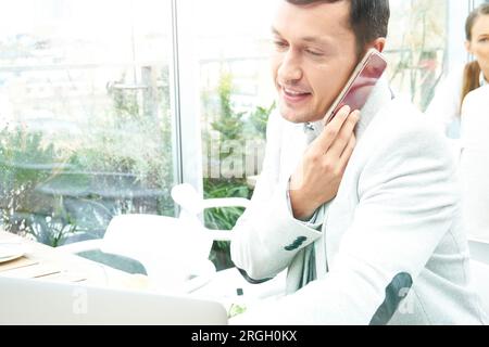 Businessman using smartphone by laptop in restaurant Stock Photo