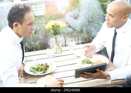 Businessmen using tablet PC during restaurant meeting Stock Photo