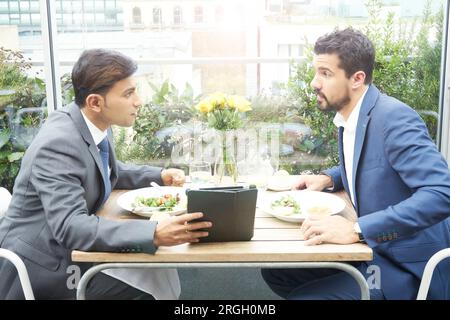 Businessmen using tablet PC during restaurant meeting Stock Photo