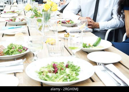 Salad and roses on set restaurant table Stock Photo