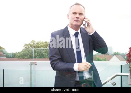 Middle-aged businessman using smartphone on balcony Stock Photo