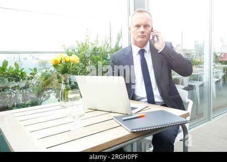 Businessman using smartphone and laptop in restaurant Stock Photo