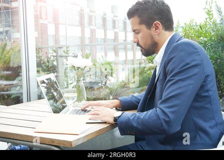 Businessman using laptop at restaurant table Stock Photo