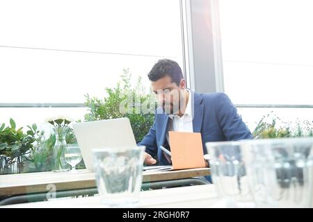 Businessman using laptop at restaurant table Stock Photo