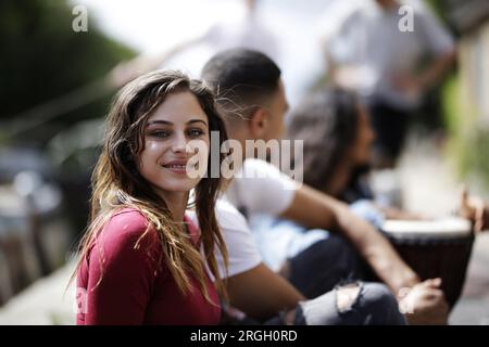 Young woman smiling outdoors with friends Stock Photo