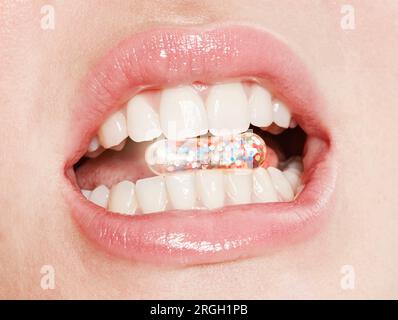 Lips of woman taking glitter capsule Stock Photo