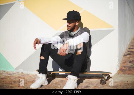Young man sitting on skateboard Stock Photo