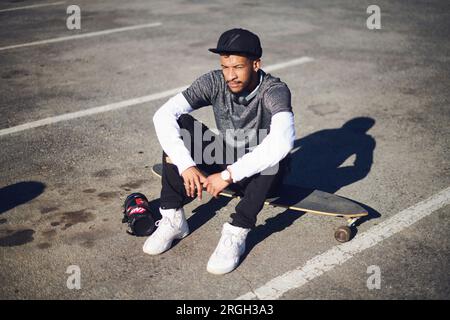 Young man with portable speaker sitting on skateboard Stock Photo