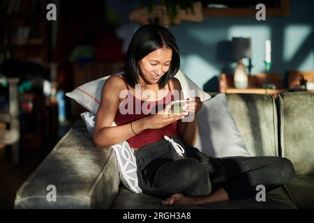 Young woman using smart phone on sofa Stock Photo