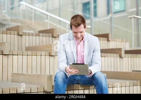 Mid adult man using digital tablet on staircase Stock Photo