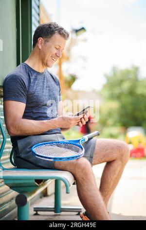 Mature man holding tennis racket and smart phone Stock Photo