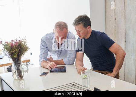 Gay couple using digital tablet in kitchen Stock Photo