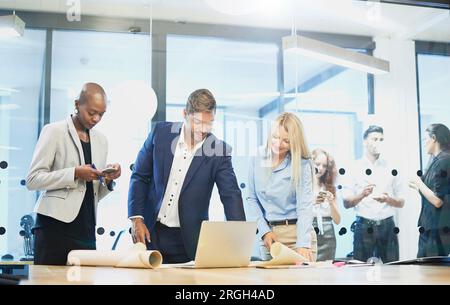 Businesspeople looking at laptop in board room Stock Photo