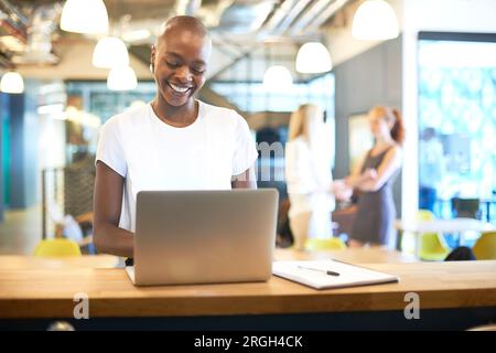 Young businesswoman smiling while using laptop Stock Photo