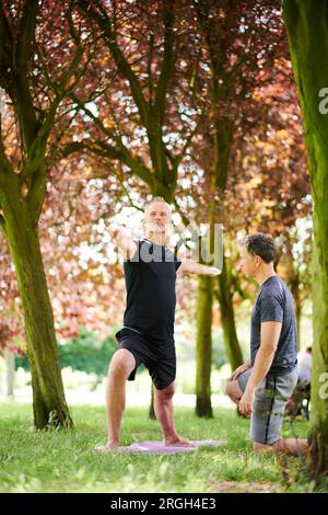 Mature men practicing yoga in park Stock Photo