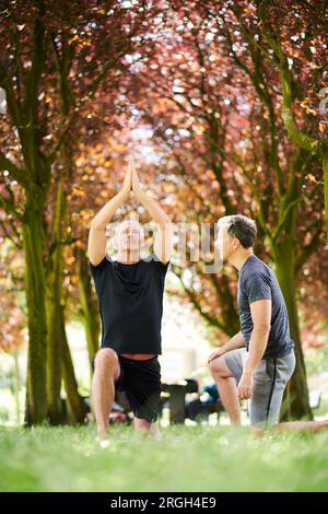 Mature men practicing yoga in park Stock Photo