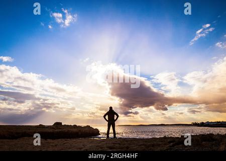 Silhouette of man standing on beach at sunset Stock Photo