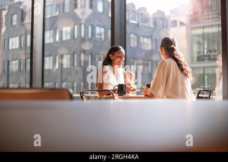 Businesswomen talking at table by window Stock Photo